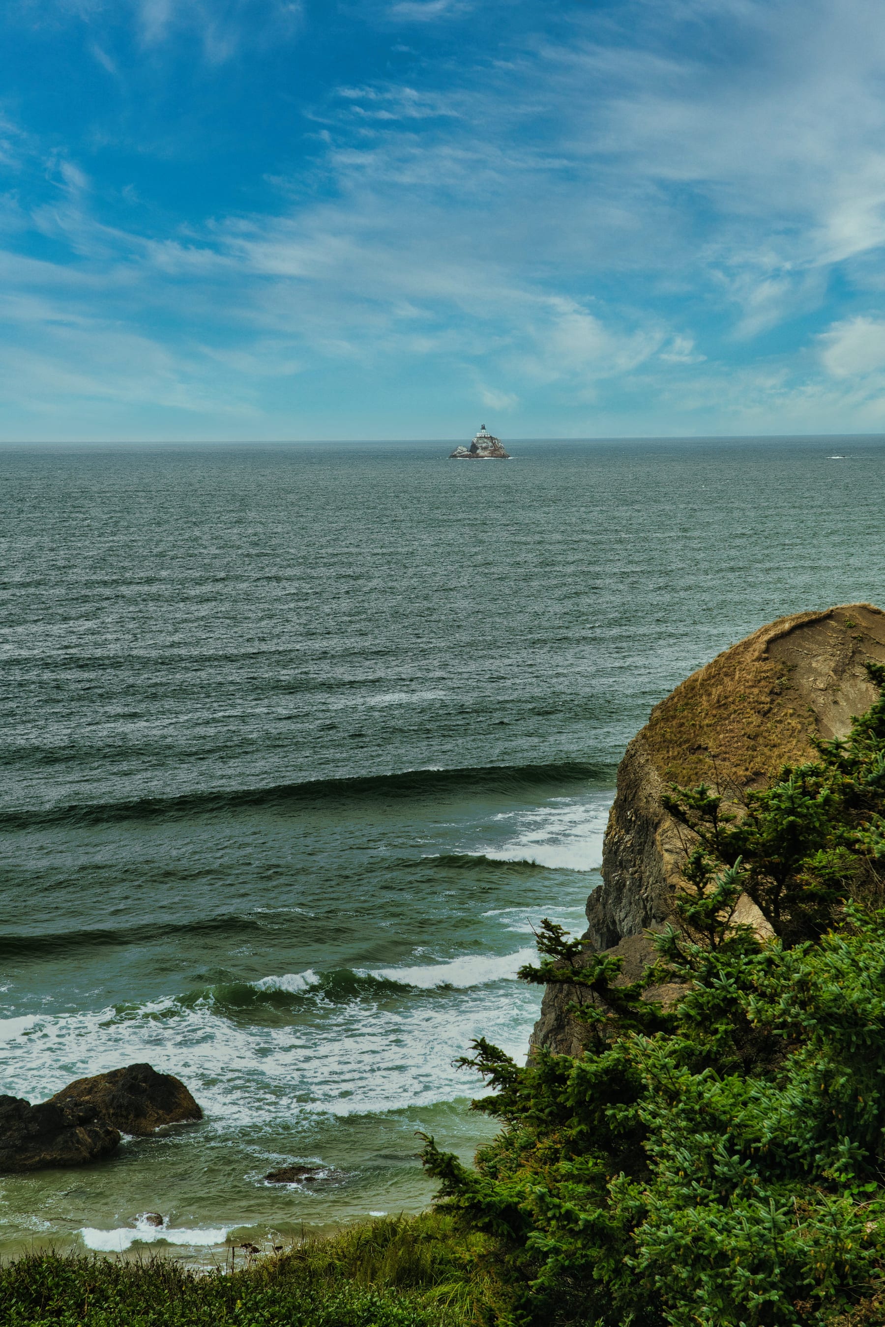 Pacific surf, evergreen cliffs, and Tillamook Rock Lighthouse off the Oregon Coast
